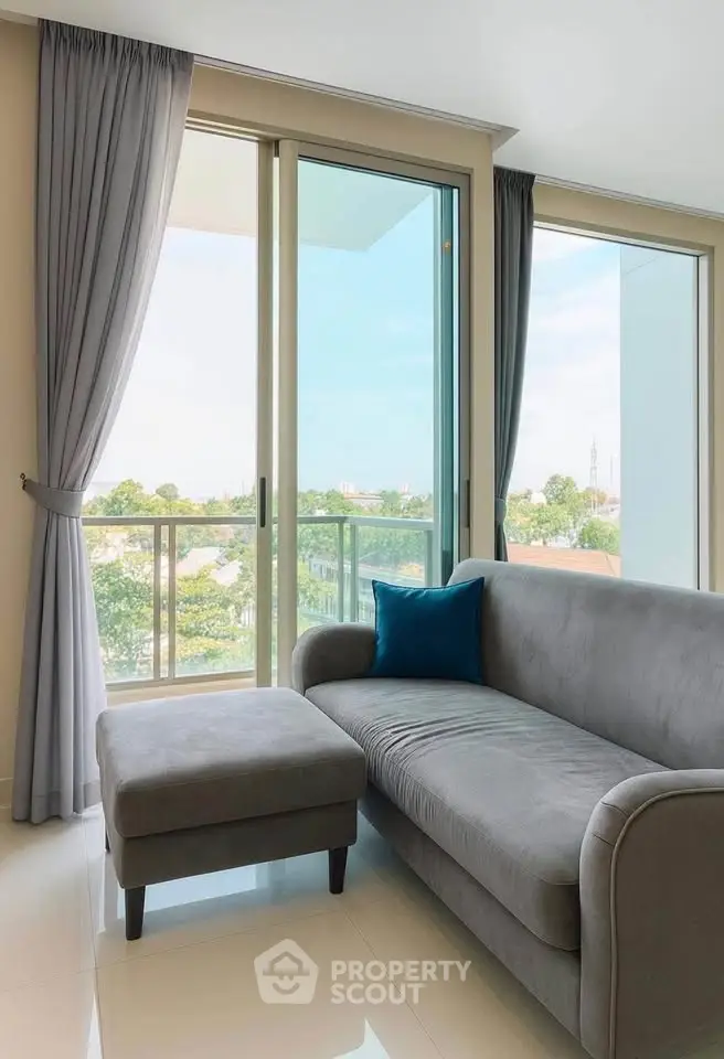 Modern living room with gray sofa and large windows offering a scenic view.