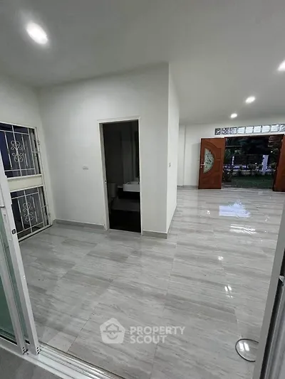 Spacious modern living area with sleek flooring and open layout, featuring elegant entrance doors.