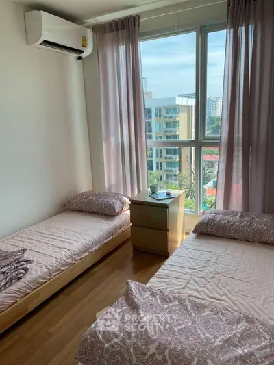 Bright bedroom with twin beds and large window offering city view