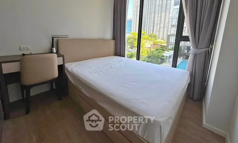 Modern bedroom with large window and city view in high-rise apartment