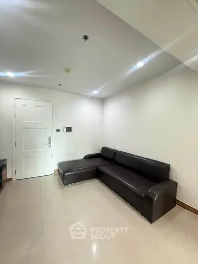 Modern living room with sleek black leather sofa and white walls, perfect for contemporary urban living.