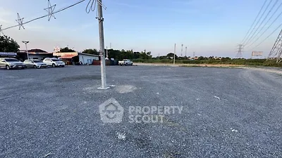 Spacious gravel parking lot with multiple cars and open sky view