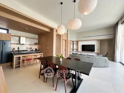 Spacious modern living room with open kitchen, stylish dining area, and elegant lighting fixtures.