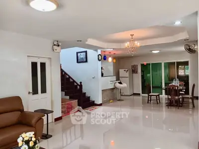 Spacious open-plan living and dining area with modern lighting and staircase.