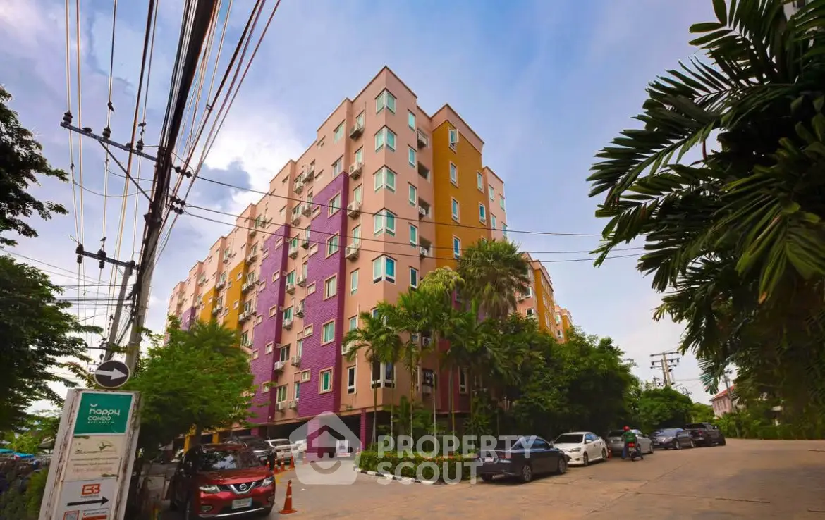 Vibrant multi-colored apartment building with lush greenery and ample parking space.