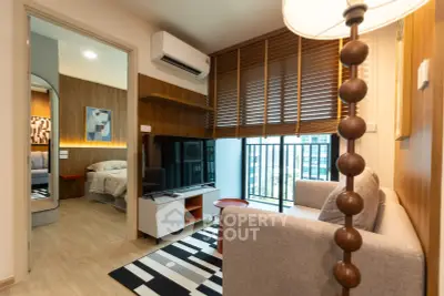 Modern living room with cozy sofa, TV, and view into stylish bedroom in urban apartment.