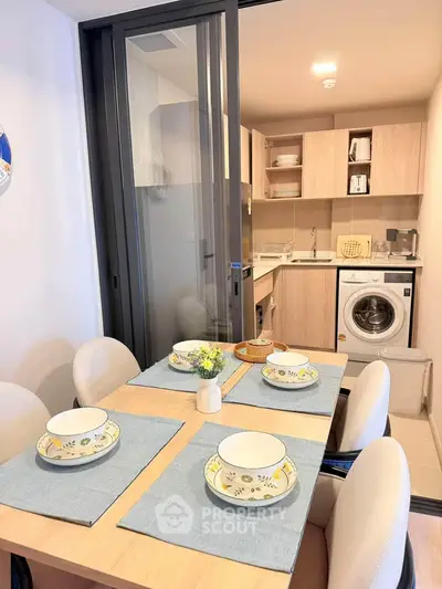 Modern kitchen with dining area featuring a washing machine and elegant table setting.