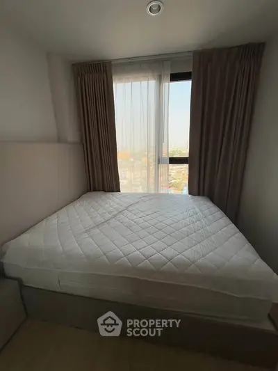Cozy bedroom with large window offering stunning city views, perfect for relaxation and comfort.