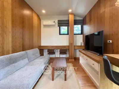 Modern living room with wooden accents, cozy sofa, and flat-screen TV, perfect for relaxation and entertainment.
