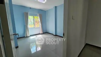 Spacious empty room with blue walls and large window, perfect for customization.