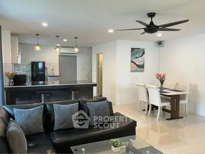 Modern open-plan living room with sleek kitchen and dining area, featuring stylish decor and ceiling fan.