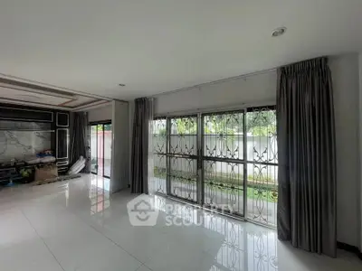 Spacious living room with large windows and garden view, perfect for natural light lovers.