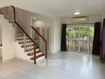 Spacious living room with staircase and large window in modern home