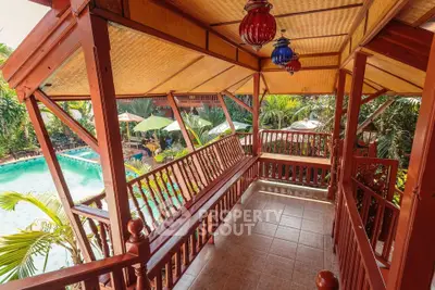 Charming wooden balcony overlooking a lush garden and inviting pool area.