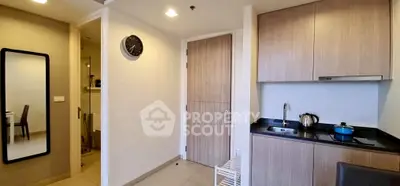 Modern kitchen with sleek cabinetry and compact design, featuring a wall clock and mirror for added style.