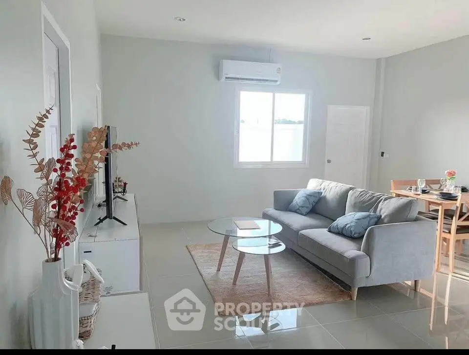 Modern living room with stylish decor and natural light, featuring a cozy sofa and elegant dining area.