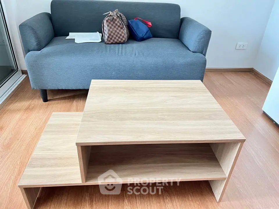 Modern living room with stylish gray sofa and wooden coffee table on sleek flooring.