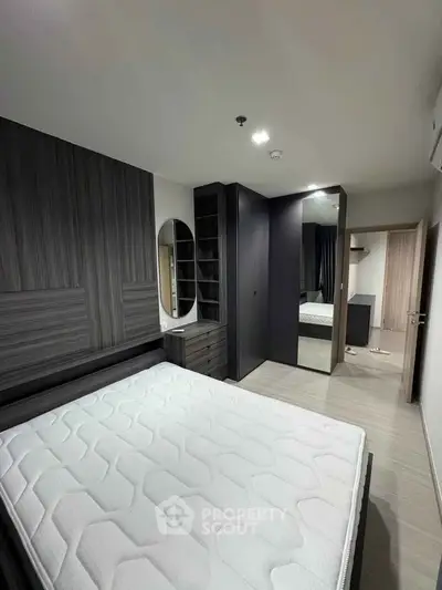 Modern bedroom with sleek design, featuring a large mirror and built-in storage solutions.