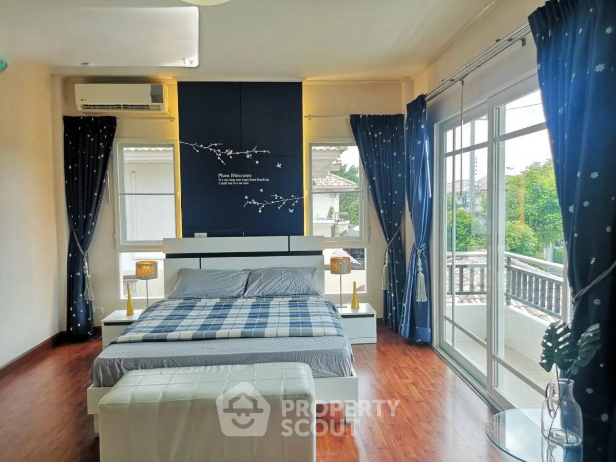 Spacious bedroom with large windows and balcony access, featuring elegant decor and natural light.