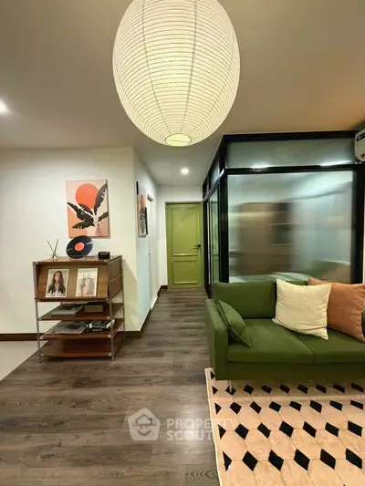 Stylish living room with modern decor, green sofa, and unique lighting in a cozy apartment.