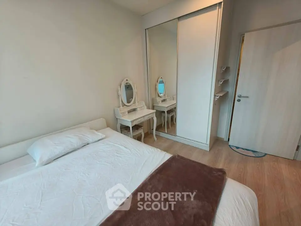 Cozy bedroom with mirrored wardrobe and elegant vanity in modern apartment.