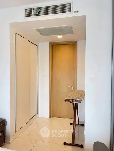 Modern apartment interior with wooden door and built-in closet, featuring sleek design and bright lighting.