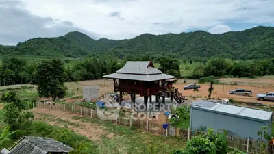 Charming elevated wooden house with scenic mountain backdrop and spacious rural surroundings.