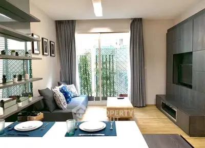 Modern living room with stylish decor and natural light, featuring a cozy sofa and sleek entertainment unit.