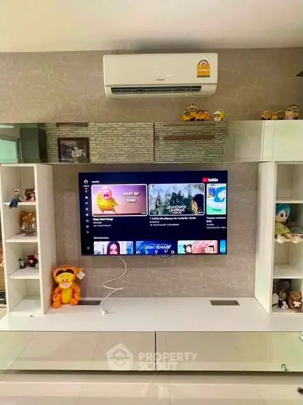 Modern living room with wall-mounted TV and air conditioning, stylish shelving, and decorative items.