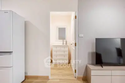 Modern apartment interior with fridge and TV, showcasing minimalist design.