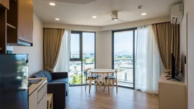Modern living room with large windows and scenic view, featuring cozy seating and dining area.