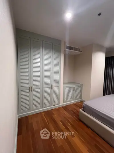 Spacious bedroom with elegant wooden flooring and built-in wardrobe, perfect for modern living.