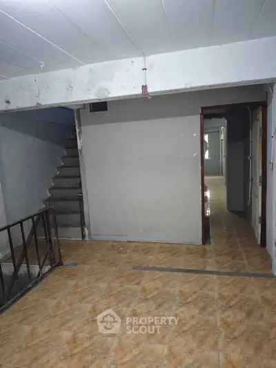 Spacious interior with tiled flooring and staircase, ideal for customization.
