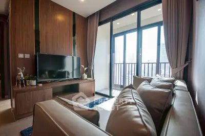 Modern living room with sleek furniture and large windows opening to a balcony with city views.