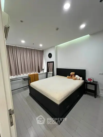 Spacious bedroom with modern decor and large window, featuring a comfortable bed and stylish furnishings.
