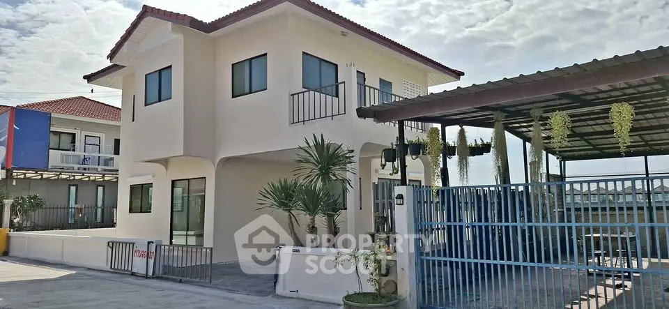 Modern two-story house with red roof and gated driveway in sunny neighborhood.