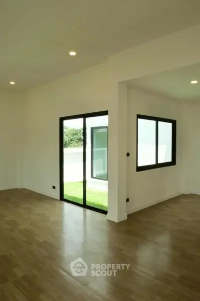 Spacious modern living room with large windows and wooden flooring