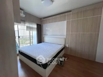 Modern bedroom with large window and city view, featuring sleek wooden paneling and a comfortable bed.