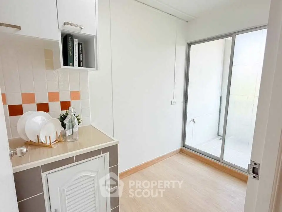 Bright kitchen area with modern design and sliding glass door to balcony.