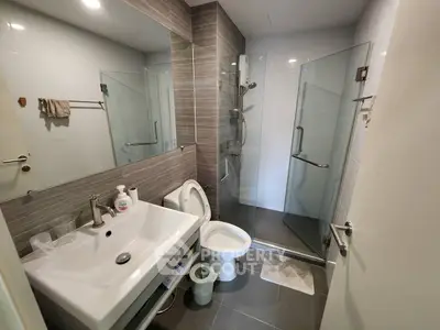 Modern bathroom with glass shower and sleek fixtures in contemporary apartment.