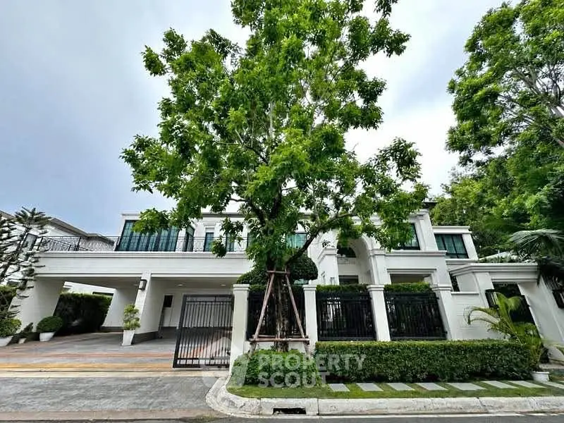 Luxurious modern villa with lush greenery and spacious driveway in prime location.