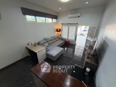 Modern living room with sleek furniture and large windows, featuring a cozy sectional sofa and wall-mounted TV.