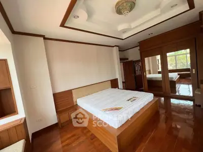 Spacious bedroom with elegant wooden flooring and built-in wardrobe, featuring a cozy bed and natural light.