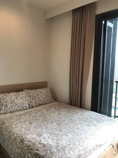 Cozy bedroom with elegant decor and balcony access in modern apartment.