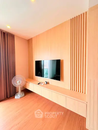 Modern living room with sleek wooden paneling and mounted TV, featuring a stylish fan and elegant decor.