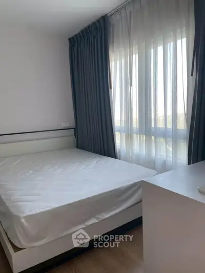 Bright bedroom with large window and modern furnishings, perfect for cozy living.