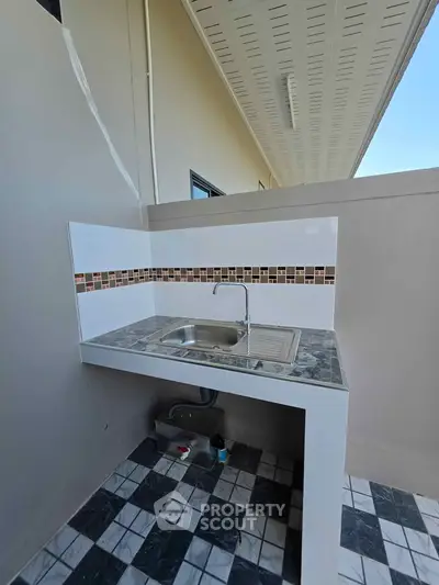 Modern outdoor kitchen sink with stylish tile backsplash and sleek design.