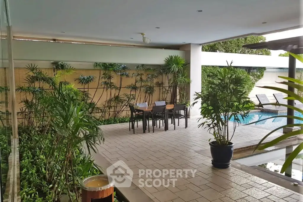 Luxurious poolside area with lush greenery and elegant outdoor seating, perfect for relaxation and entertainment.