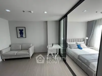 Modern apartment with stylish living room and cozy bedroom separated by glass wall.