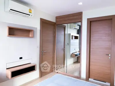 Modern bedroom with wooden doors, mirrored closet, and air conditioning unit.